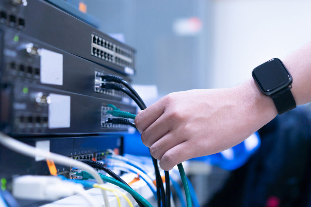 Close-up on engineering man hand trying to checking LAN to switch layer 2 for sharing file and networking at data center operating telecommunication for technology industry and business concept